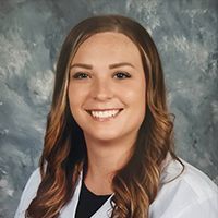 A woman in a white lab coat is smiling for the camera.