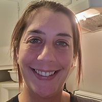 A close up of a woman 's face smiling in a kitchen.