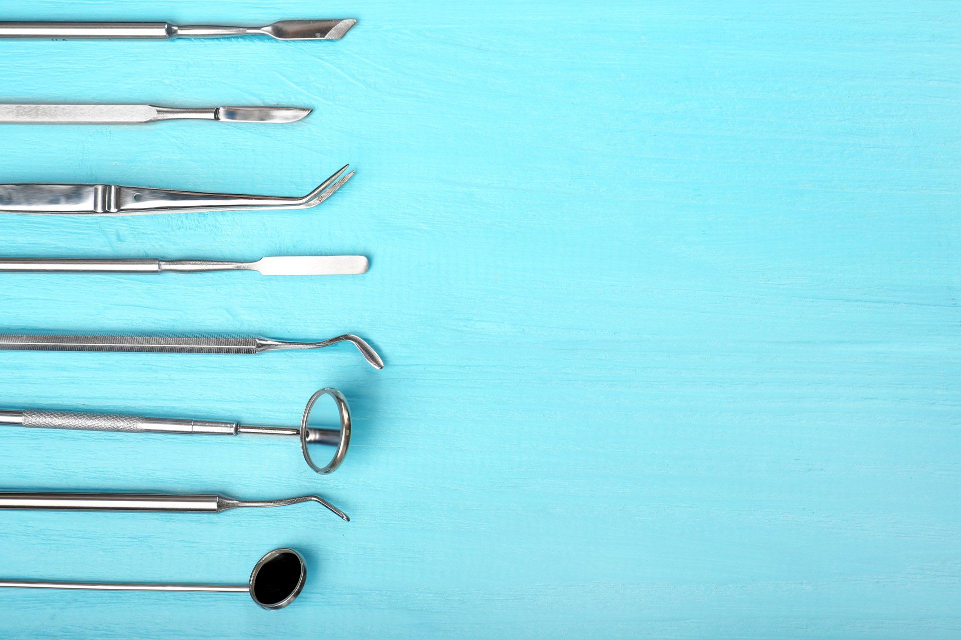 A row of dental instruments on a blue background.