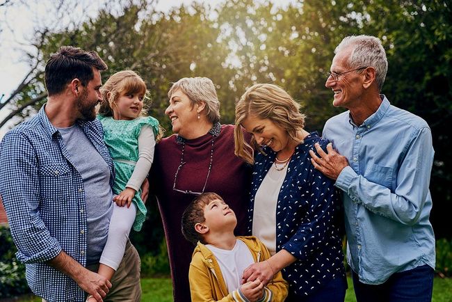 A large family is standing next to each other in a park.