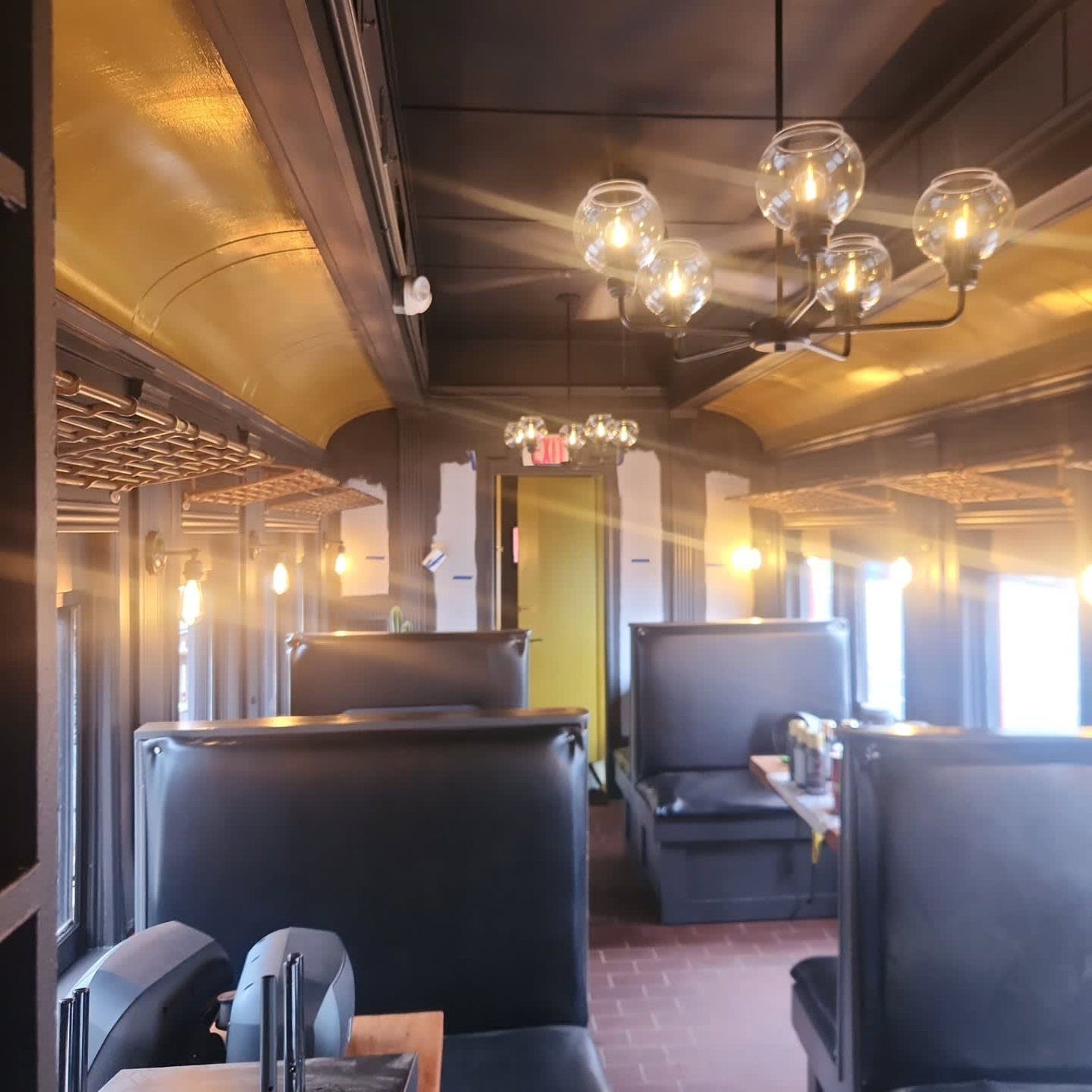 Restaurant interior with booths, decorative lighting, and a yellow ceiling.