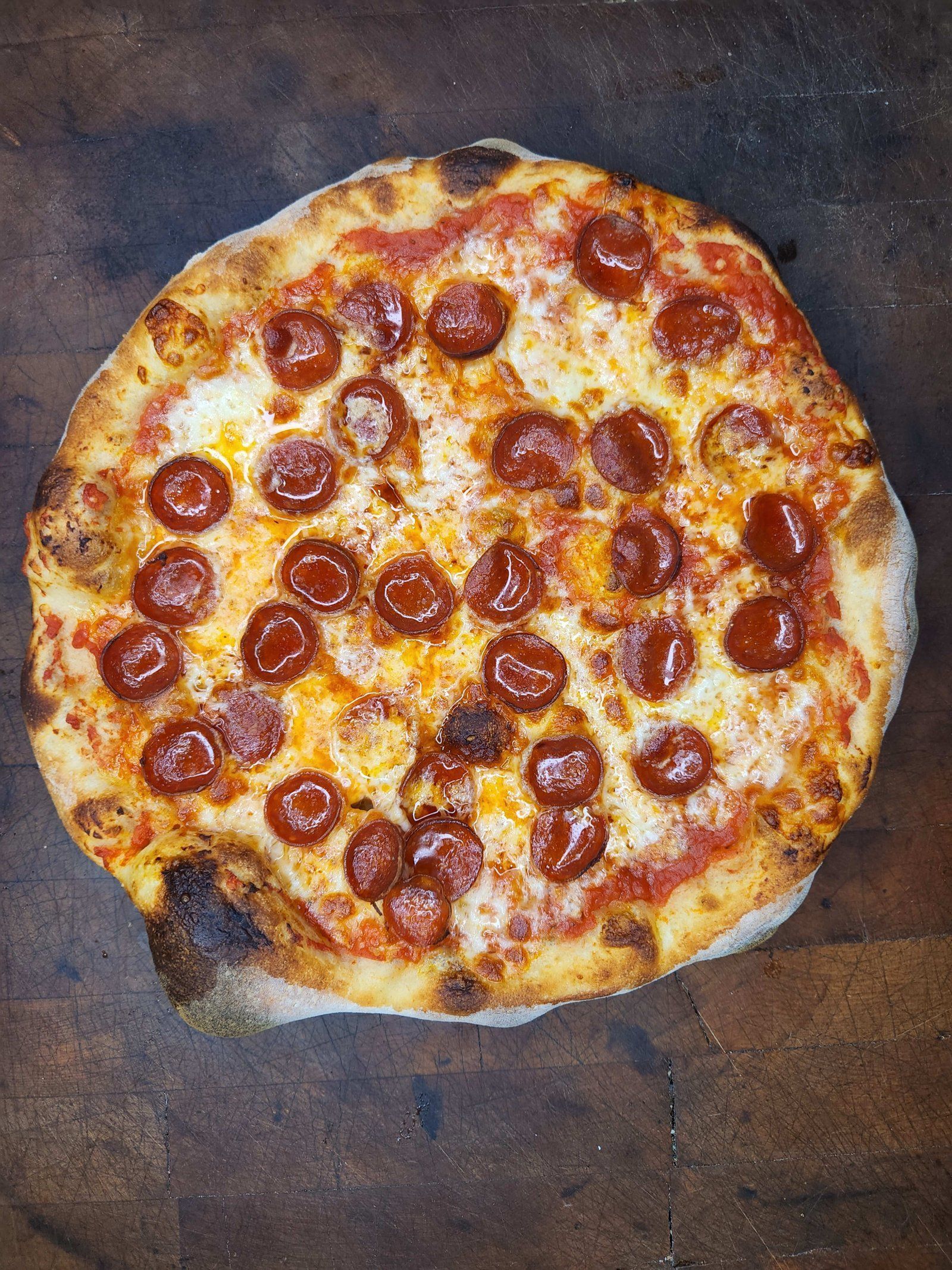 Pepperoni pizza on a dark wooden surface.