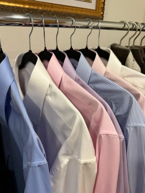Shirts of various colors hanging on a clothing rack.