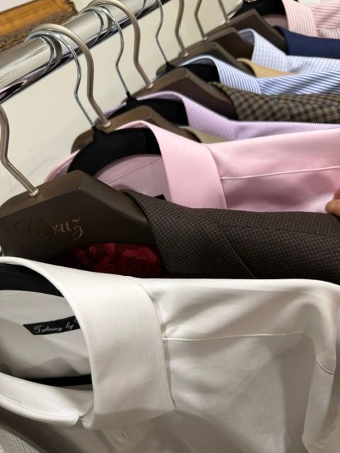 Close-up of dress shirts in various colors hanging on a clothing rack.