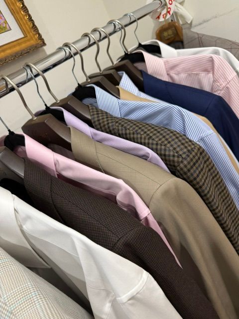 Clothes hanging on a rod: jackets and button-down shirts in various colors.