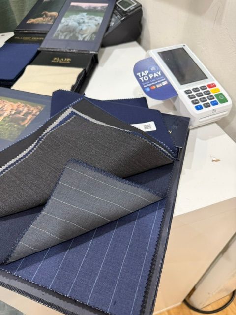Fabric swatches and payment terminal on a white surface, showcasing different suit material options.