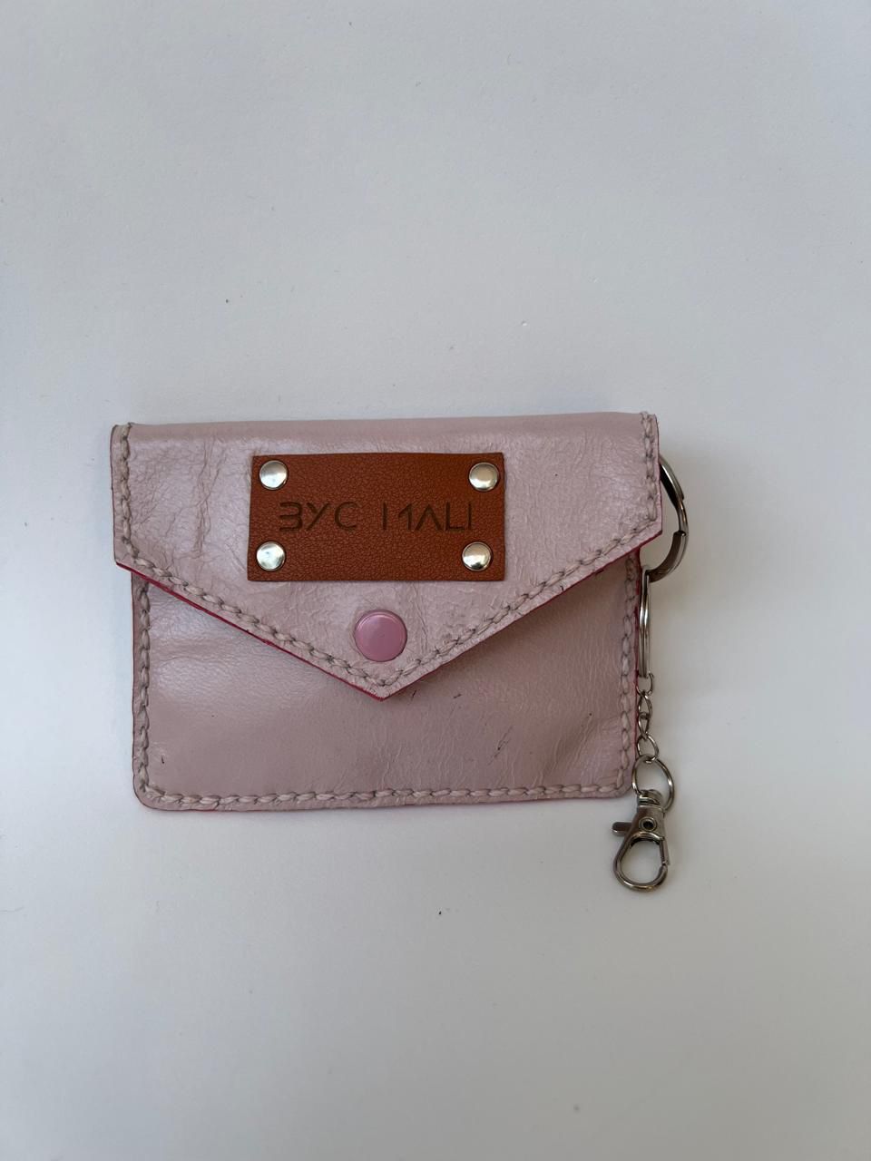 Cartera de piel color rosa pálido con parche marrón, cierre a presión y llavero.