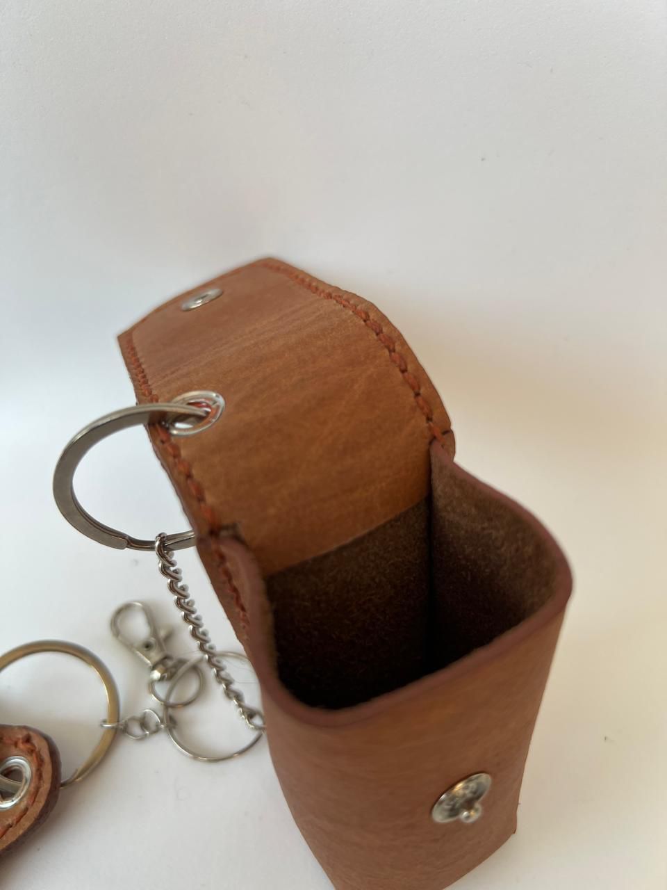 Llaveros de cuero marrón: un porta lápiz labial y un espejo.