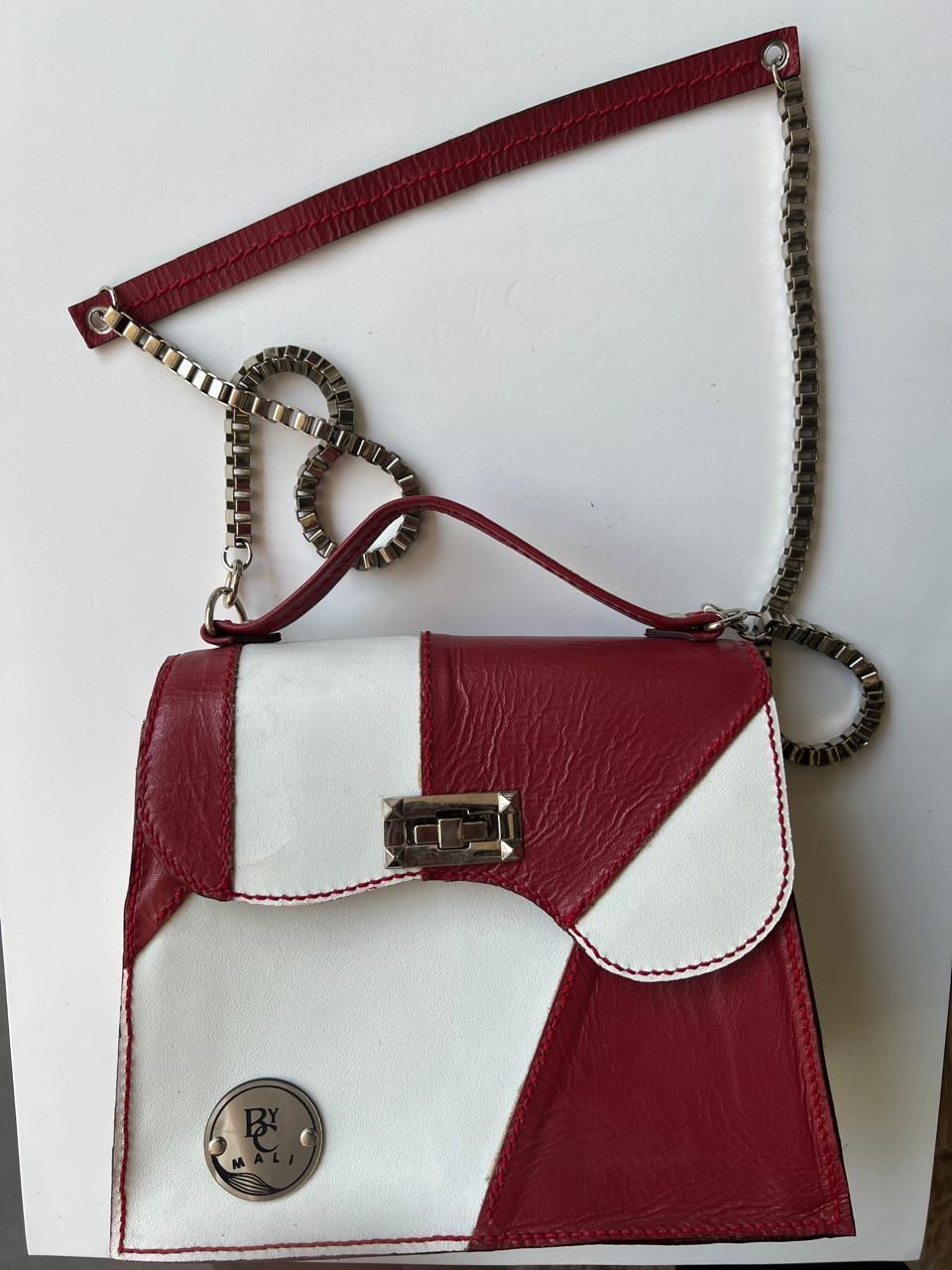 Bolso de mano de patchwork rojo y blanco con asa de cadena.