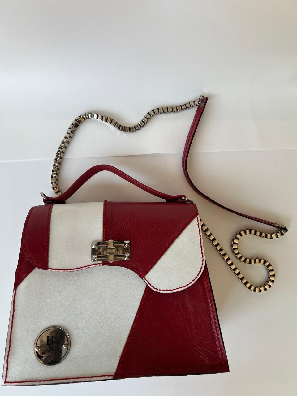 Bolso de mano de patchwork rojo y blanco con asa de cadena.