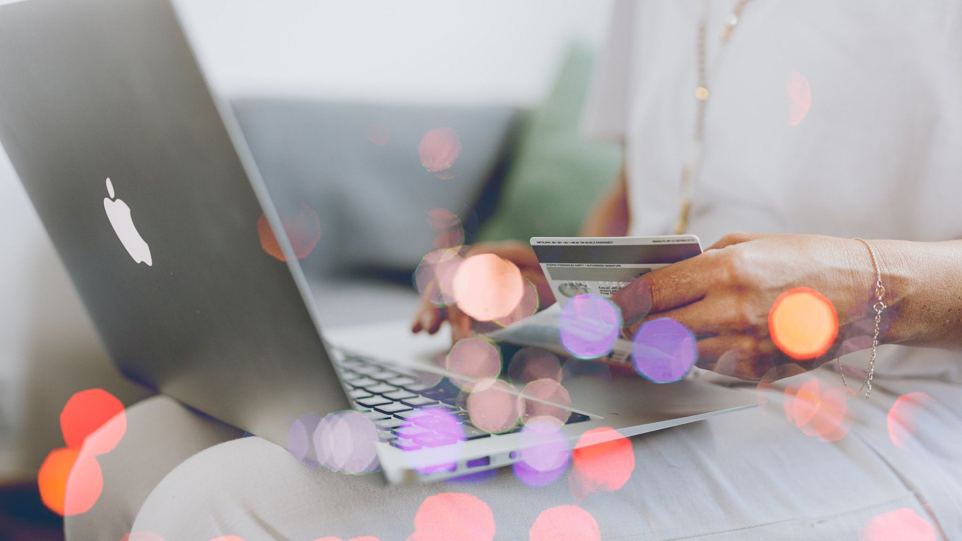 a woman is holding a credit card while using a laptop computer .