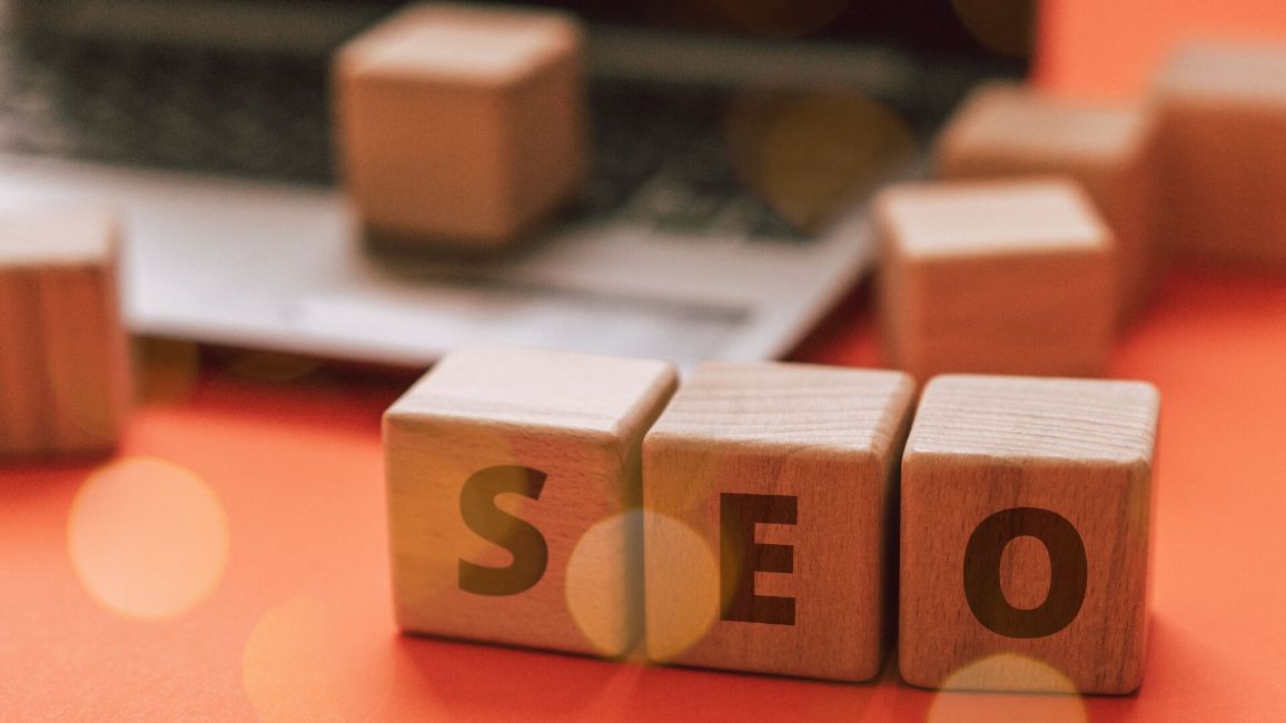 the word seo is written on wooden blocks in front of a laptop .