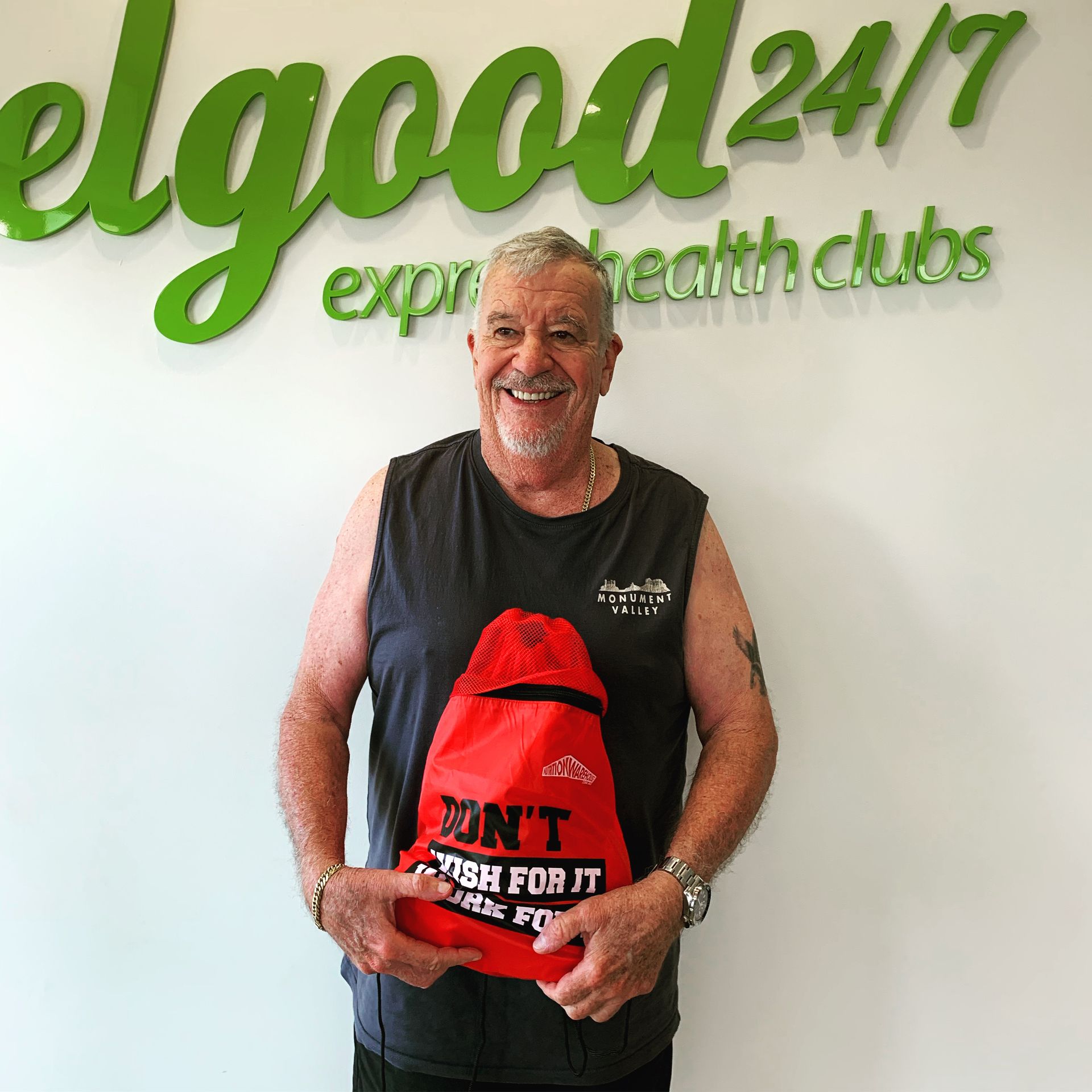 Man Holding Red Bag and Smiling — ifeelgood 24/7 Oxenford In Oxenford, QLD