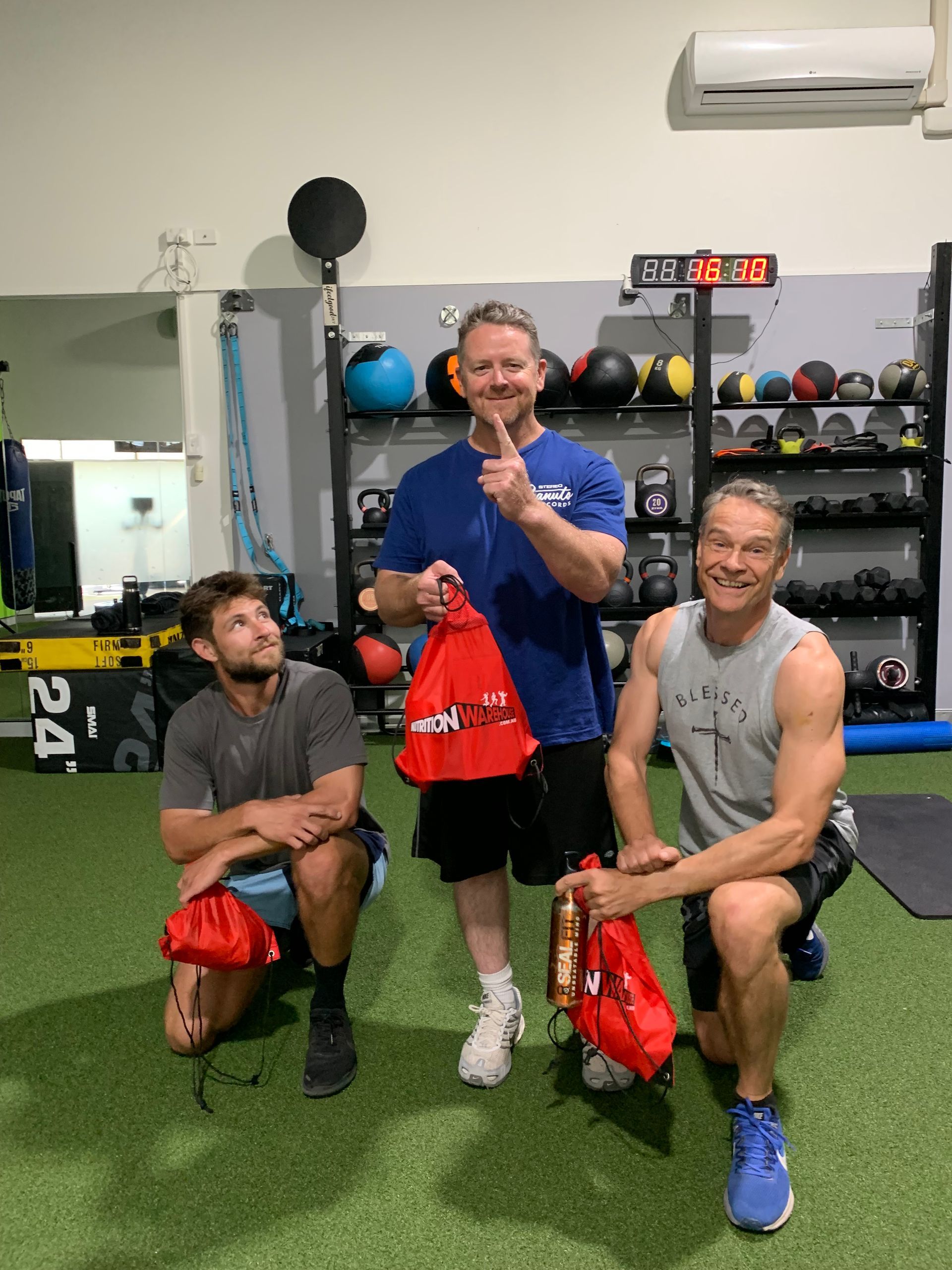 Group of men posing with red bags in their handβ ifeelgood 24/7 Oxenford In Oxenford, QLD