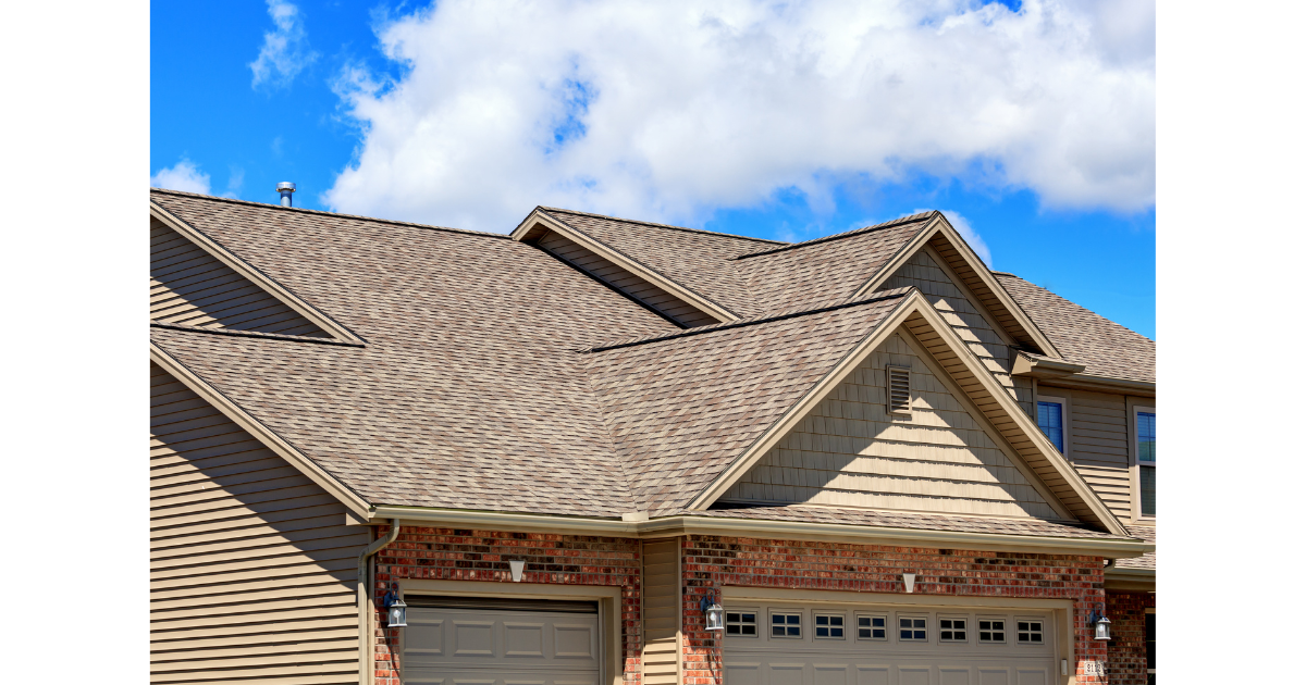 The roof of a house with a garage door and a blue sky in the background.