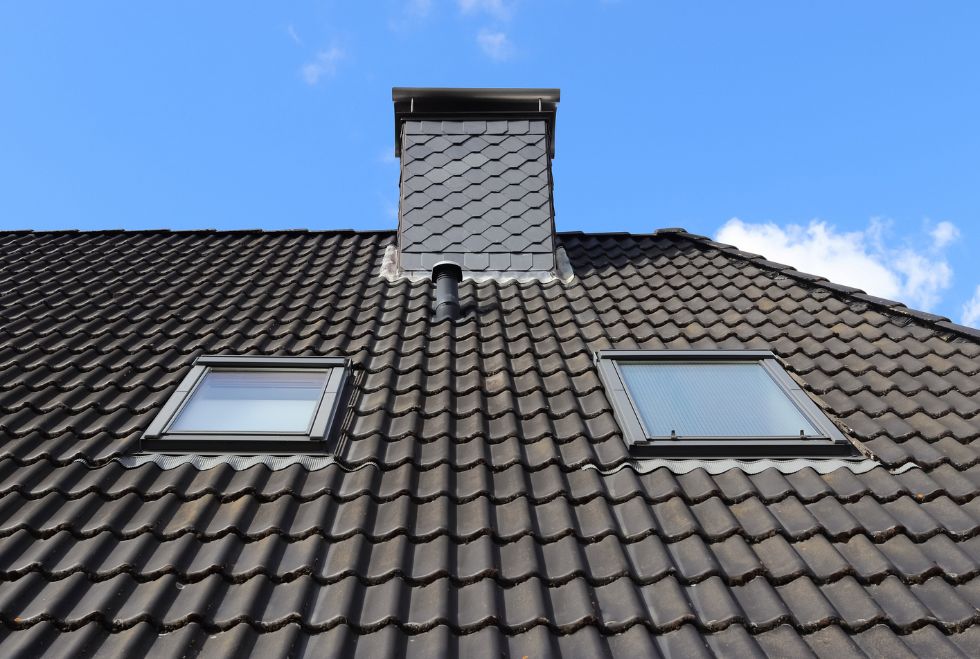 A roof with two skylights and a chimney on it.