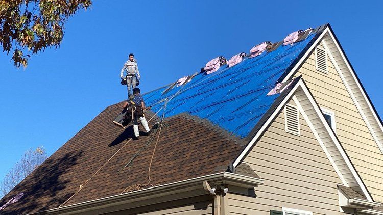 contractor repairing shingles on a roof.