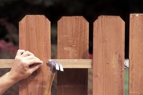 A Person Is Hammering a Nail Into a Wooden Fence — Nuevo, CA — Golden West Fence