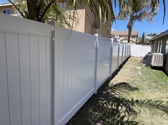 A White Vinyl Fence Is in The Backyard of A House — Nuevo, CA — Golden West Fence
