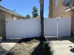 A White Fence Is Sitting Next to A Tree in Front of A House — Nuevo, CA — Golden West Fence