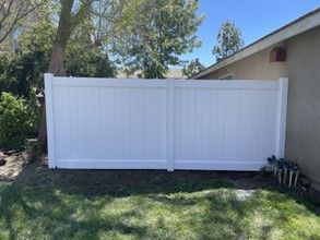 A White Vinyl Fence Is Sitting in The Grass in Front of A House — Nuevo, CA — Golden West Fence