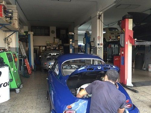 Meccanico ripara una macchina blu con il baule aperto