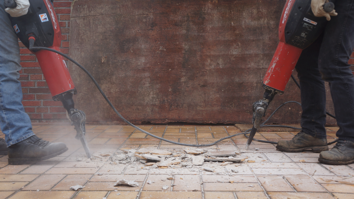 A yellow excavator is demolishing a building.
