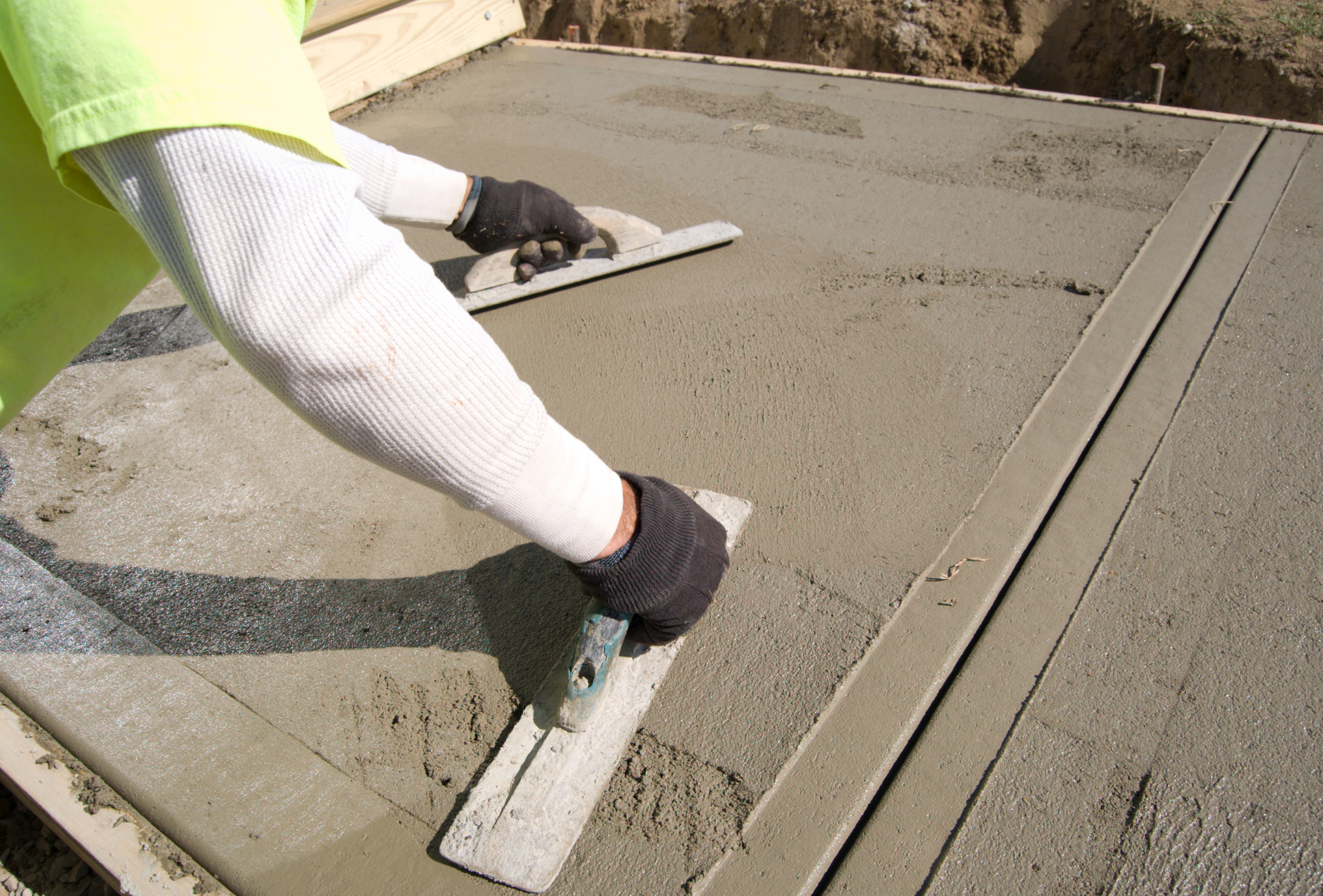 A person is spreading concrete with a trowel