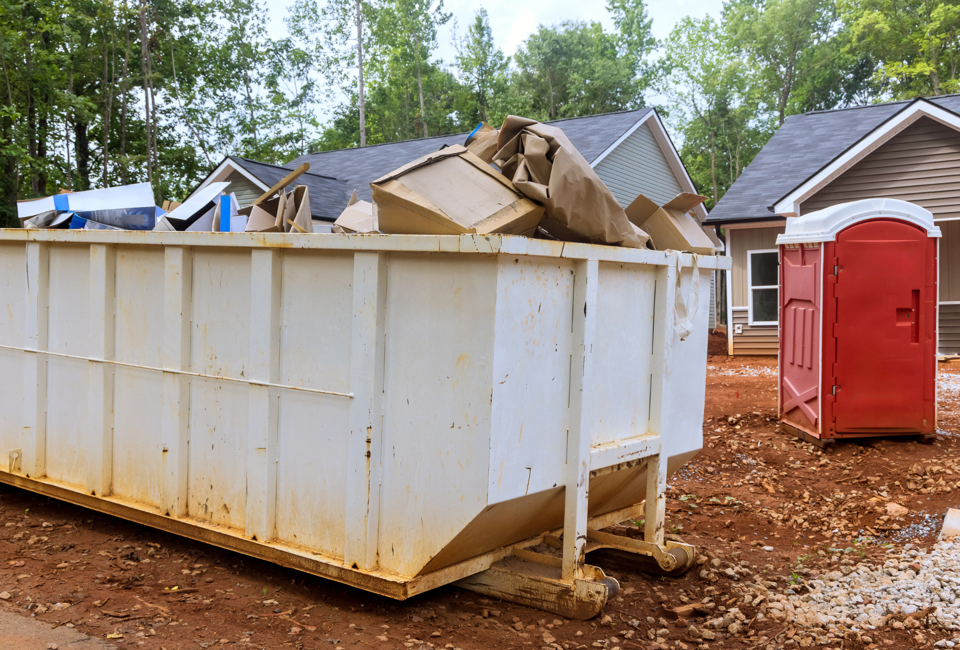 A large dumpster is sitting in front of a house under construction.