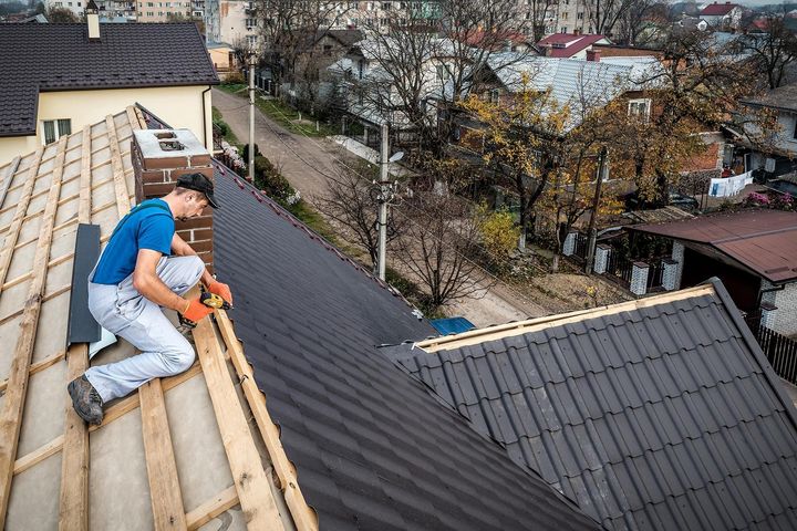 a man is working on the roof of a house .