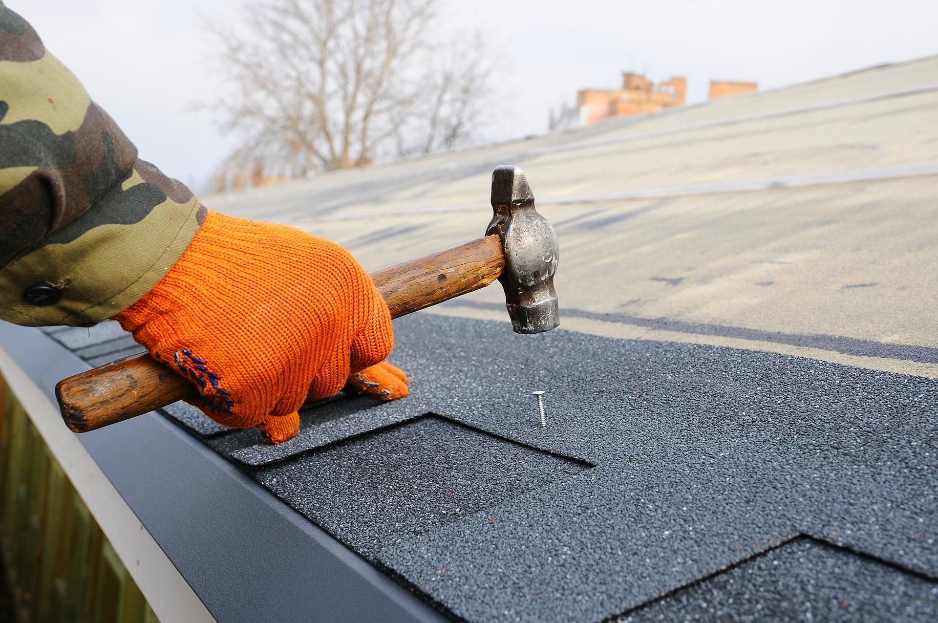 a person is hammering a nail into a roof with a hammer .