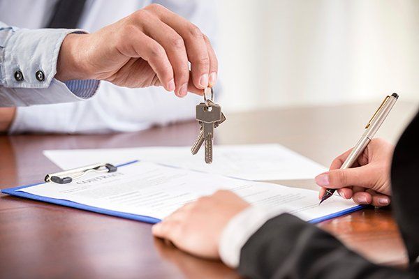 A property manager hands a set of keys to a new tenant.