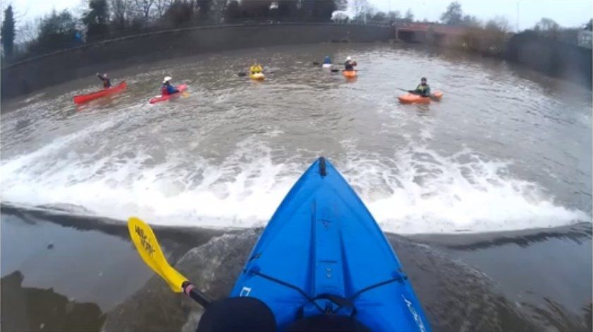 Photo of kayak poised above weir
