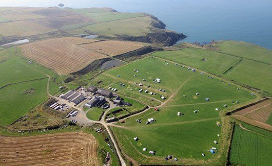Aerial view of Celtic Camping farm buildings with sea in distance
