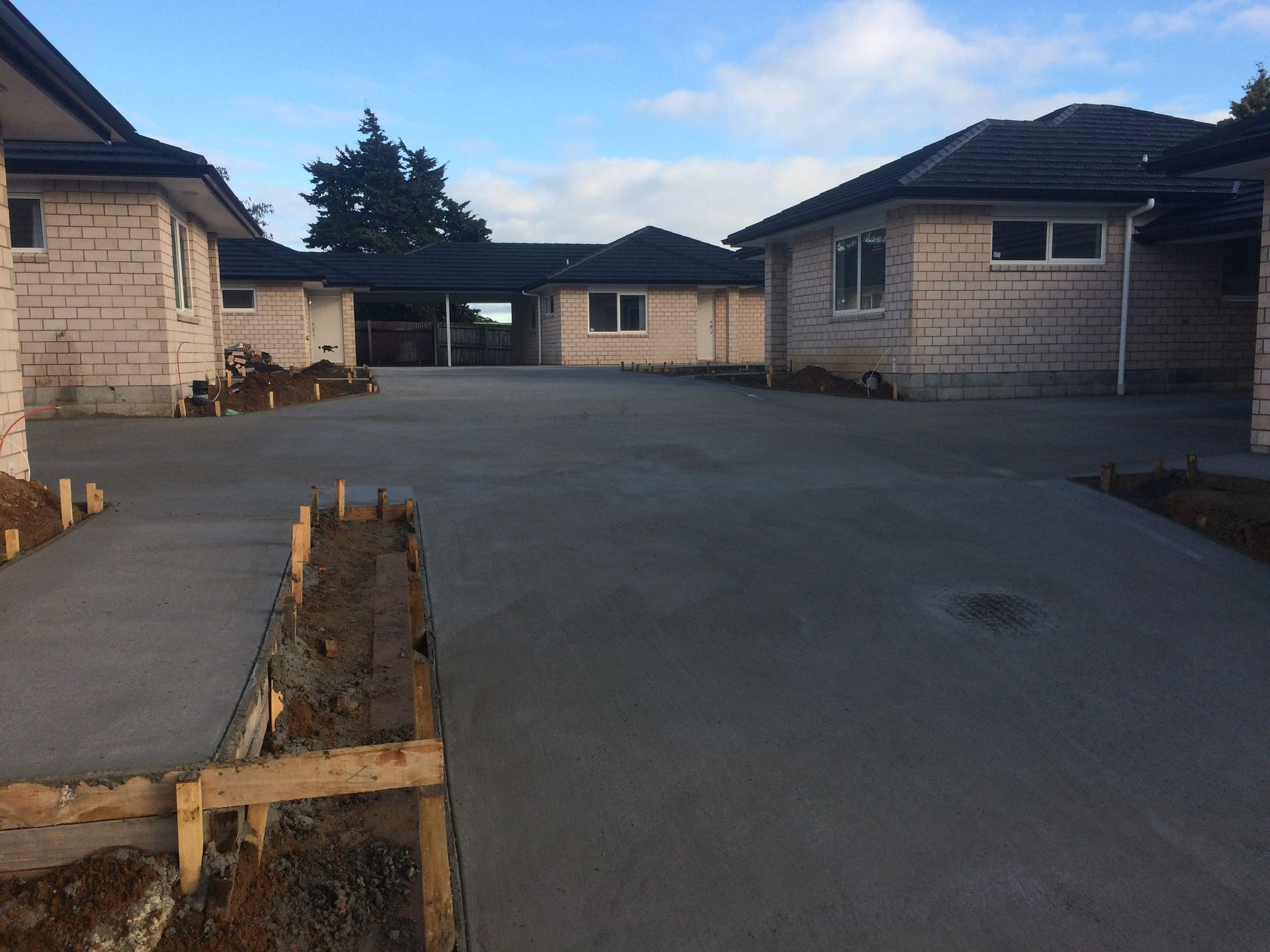 Newly poured concrete driveway with houses under construction.