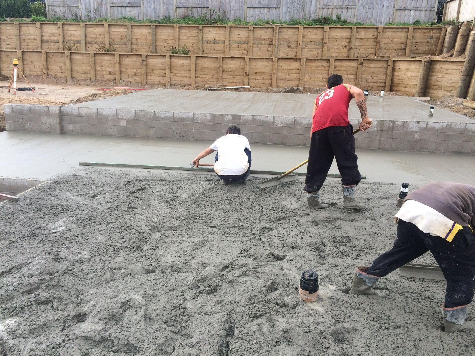 Construction workers leveling wet concrete at a building site.