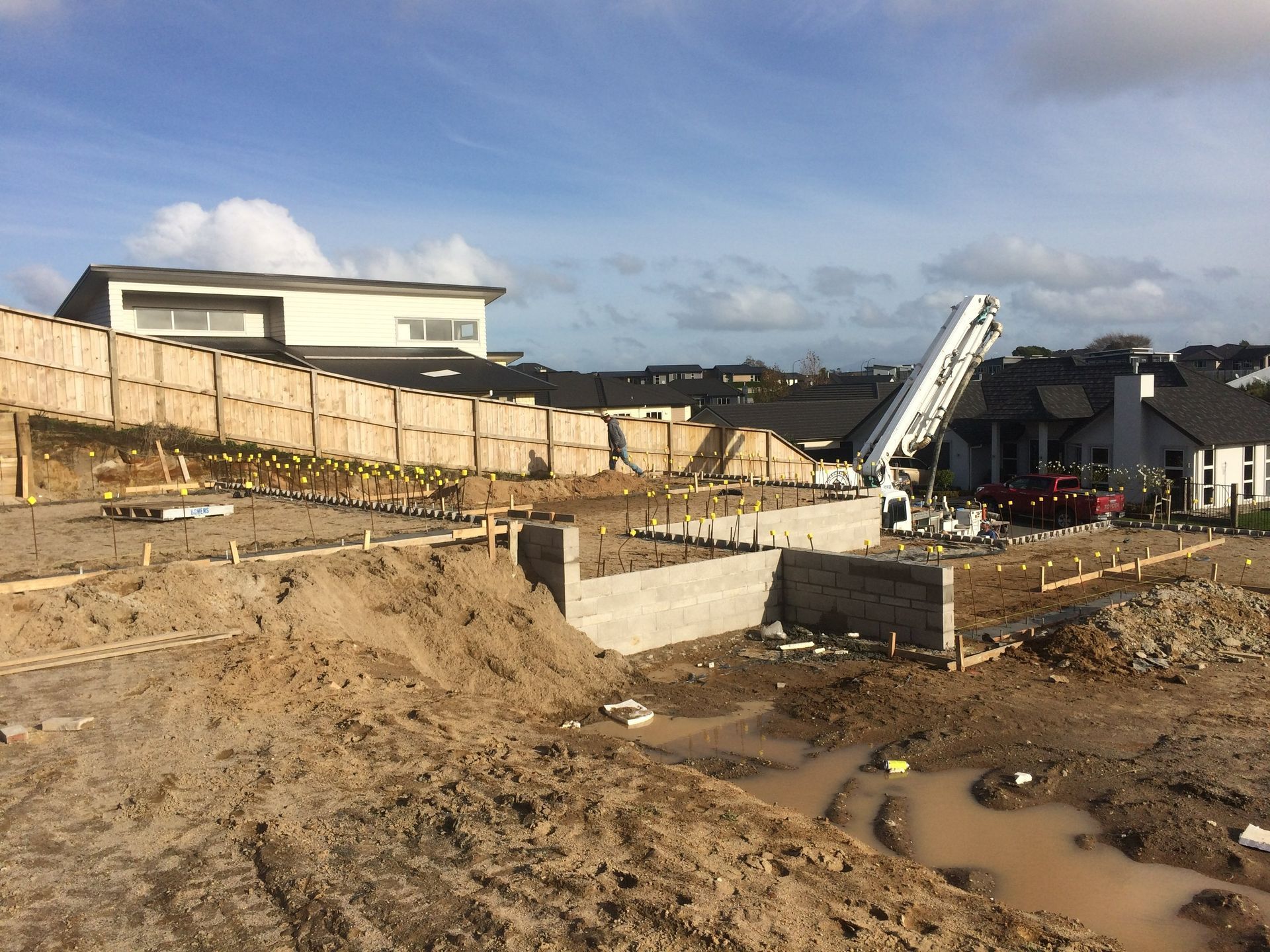 Construction site with foundation walls, concrete pump, and fencing.