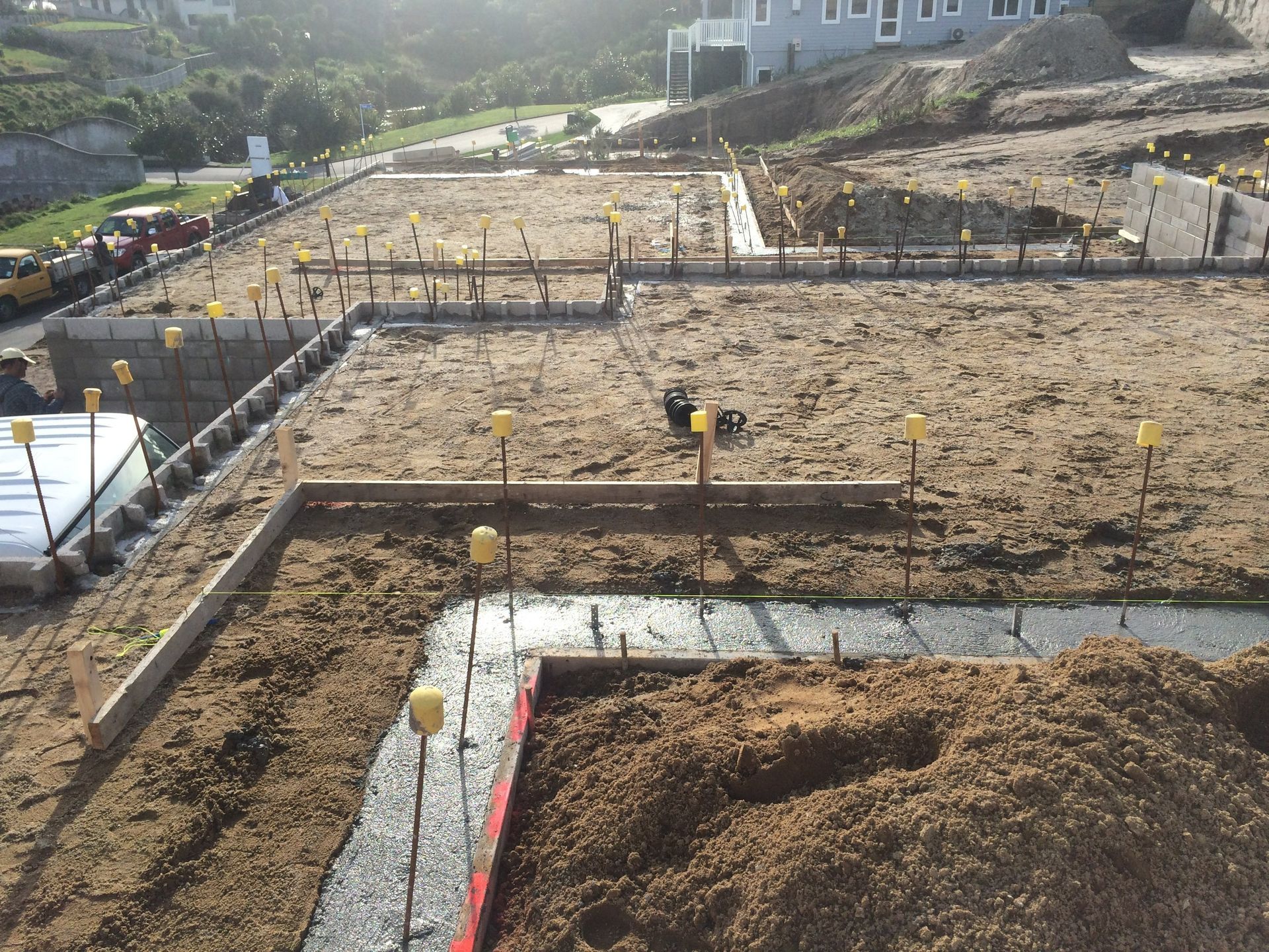 Construction site with wooden forms for foundations, filled with dirt; yellow markers.