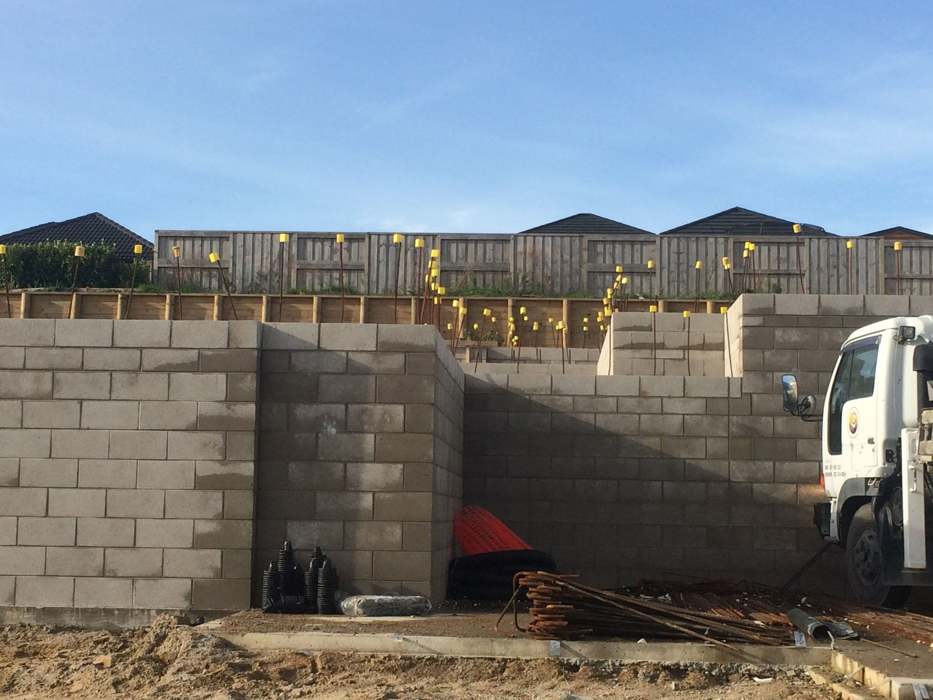 Construction site: concrete block walls being built; truck in foreground, fence in background.