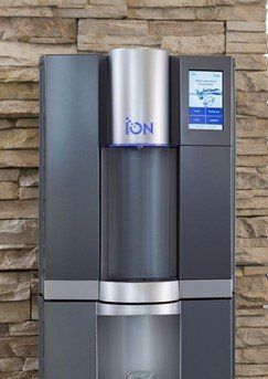 A water dispenser is sitting in front of a stone wall.