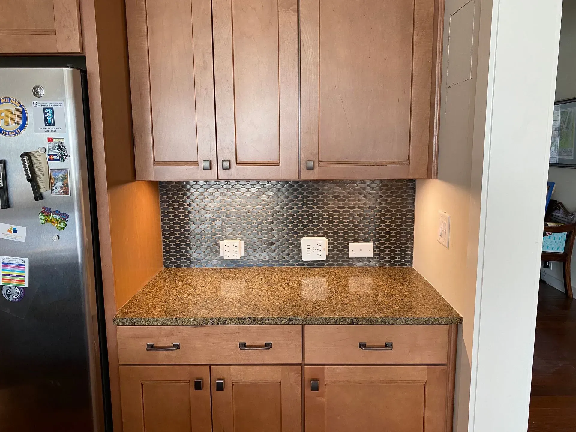 Kitchen cabinets with granite countertop, tiled backsplash, and outlets.