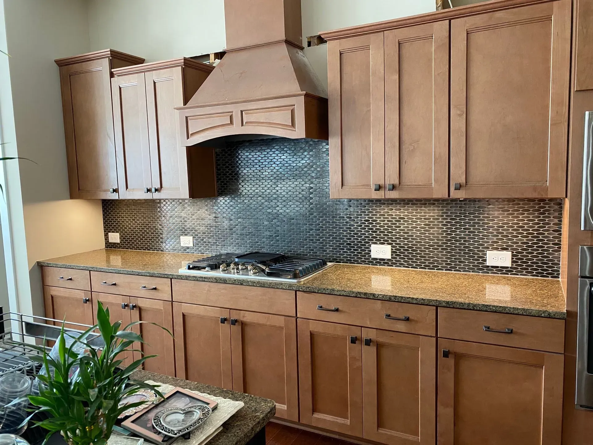 Kitchen with brown cabinets, granite countertops, and patterned backsplash.
