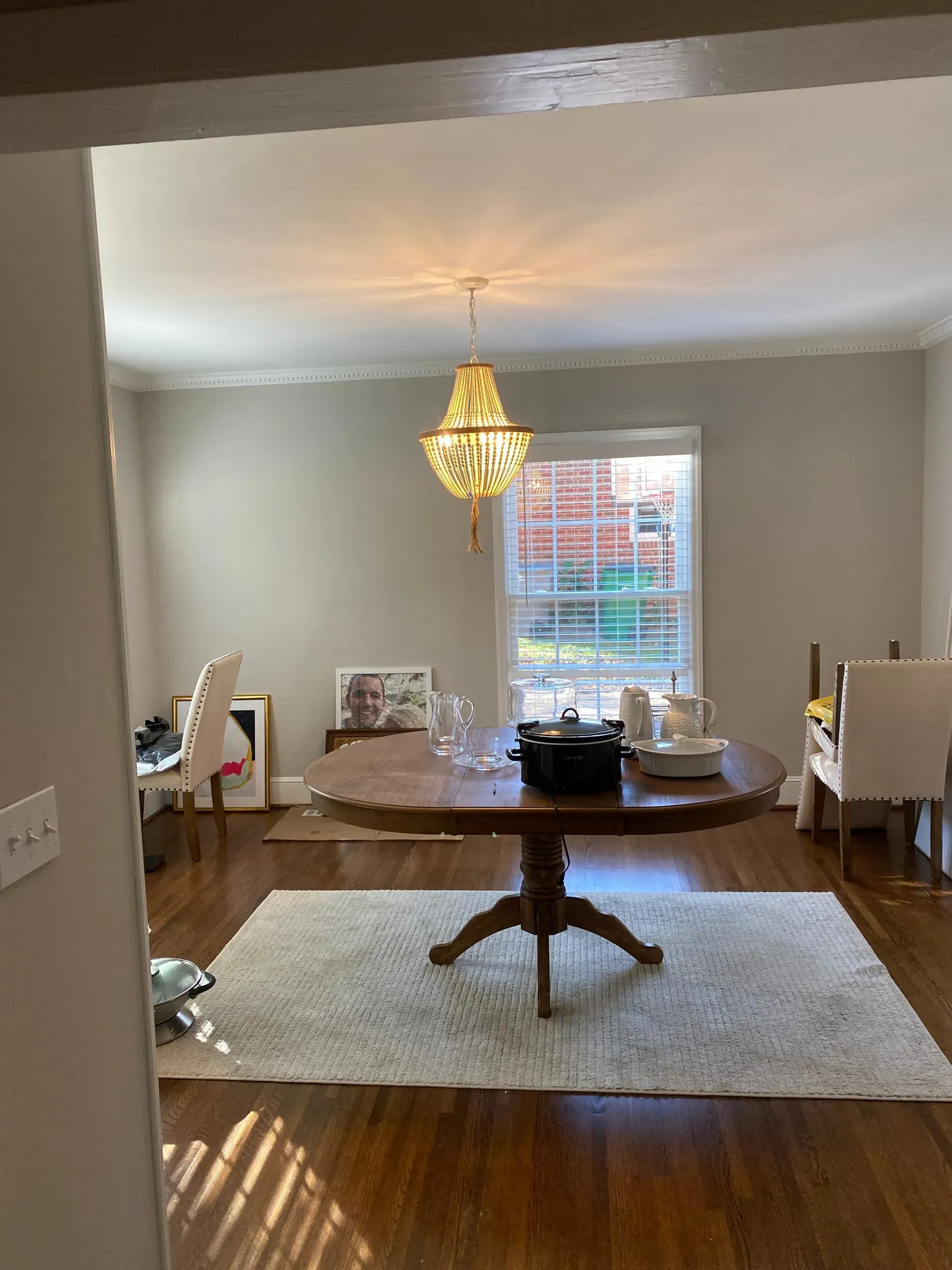 Dining room with round wooden table, chandelier, rug, and chairs.