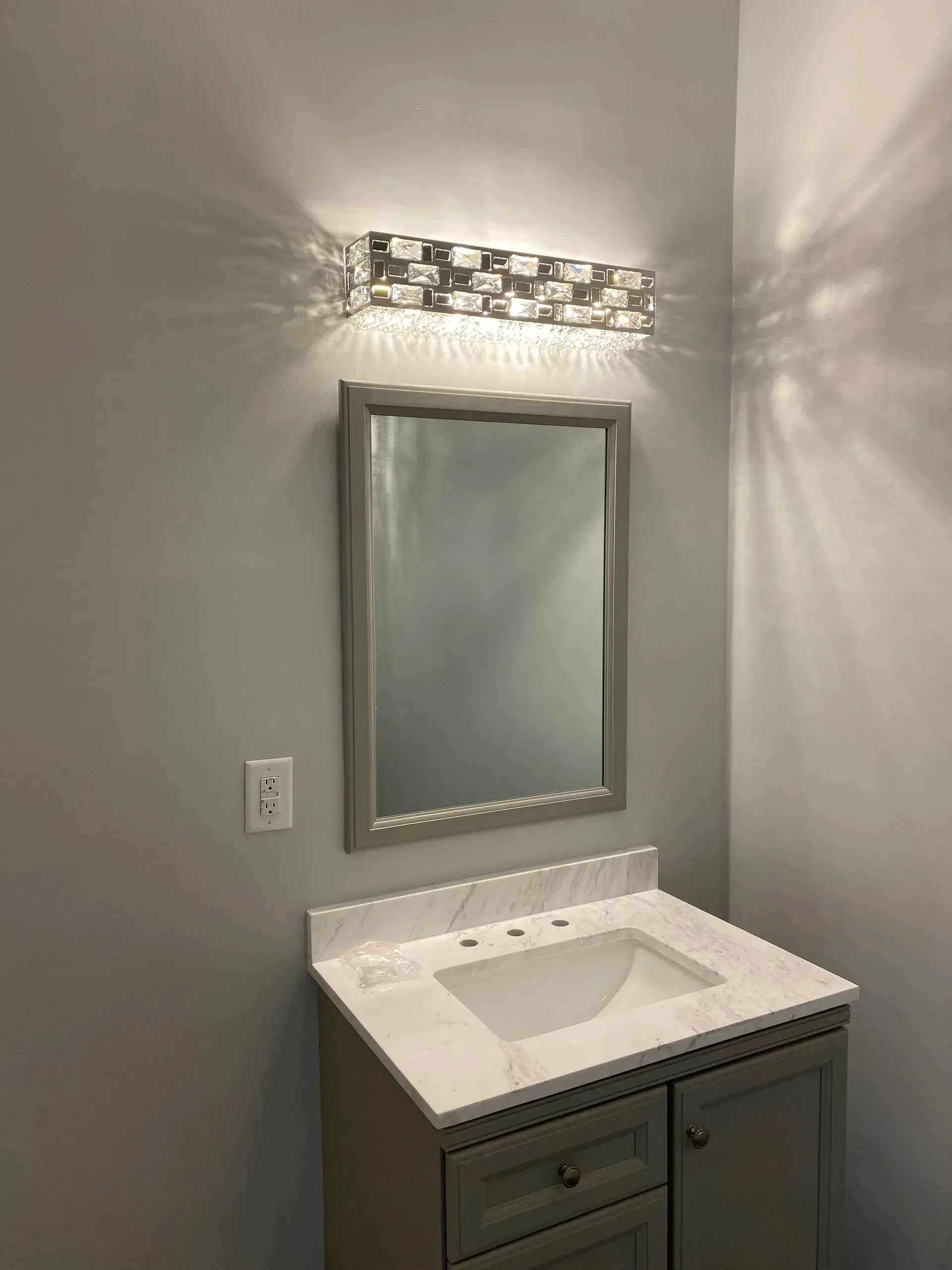 Bathroom with gray walls, vanity with marble-look countertop, mirror, and decorative light fixture.