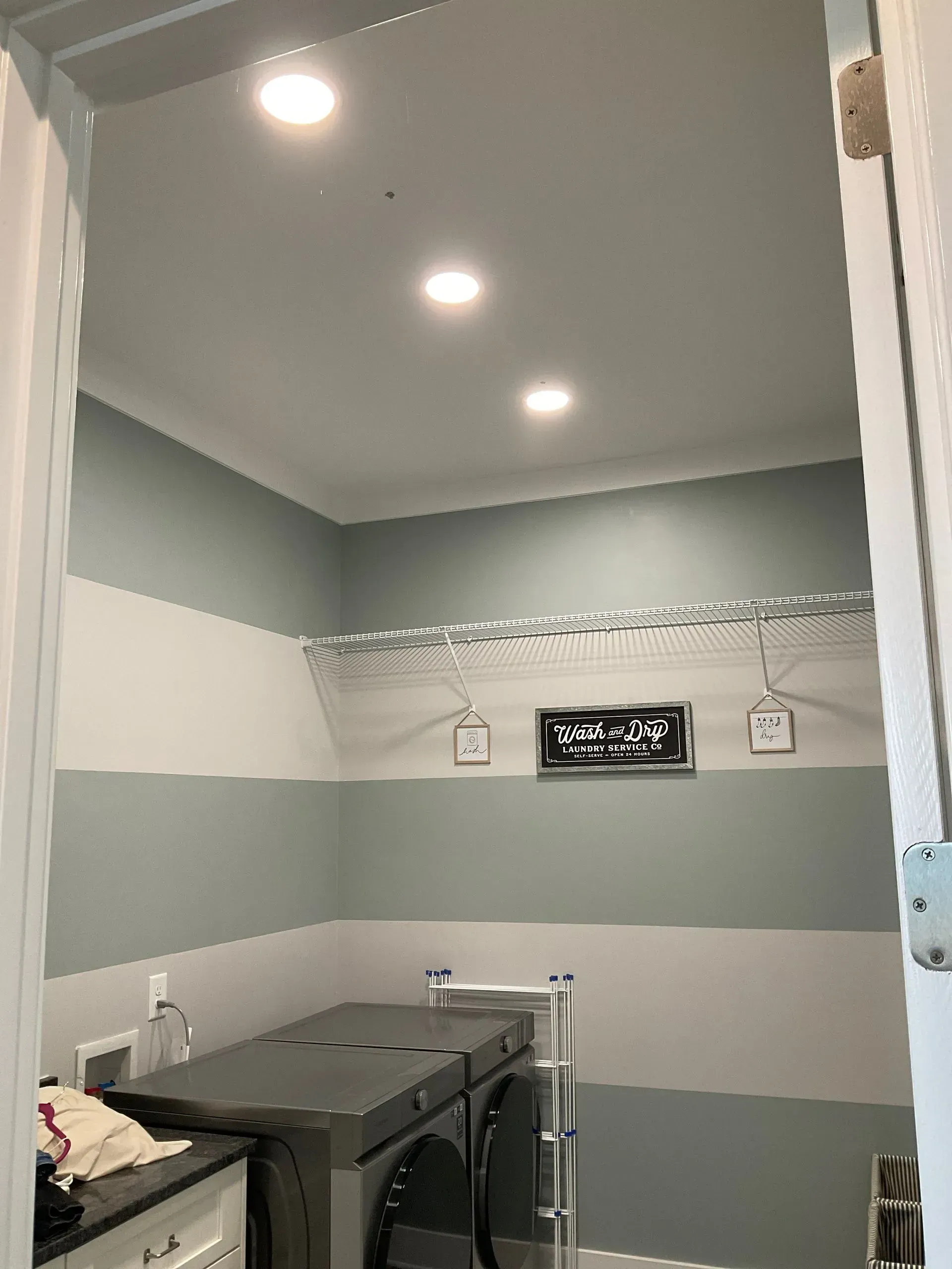 Laundry room with gray and white striped walls, washer and dryer, and three ceiling lights.