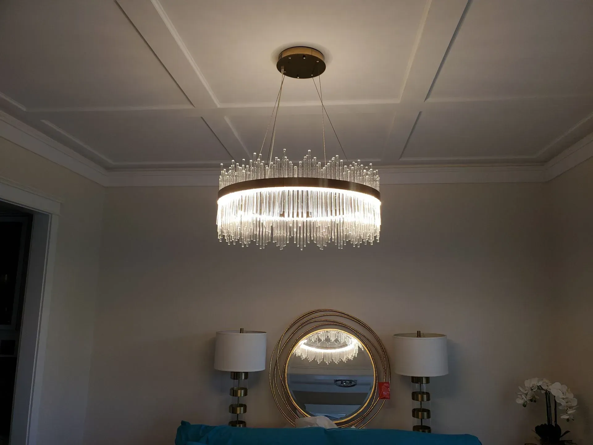 Crystal chandelier hanging above a table with a mirror and lamps, reflecting in the mirror.