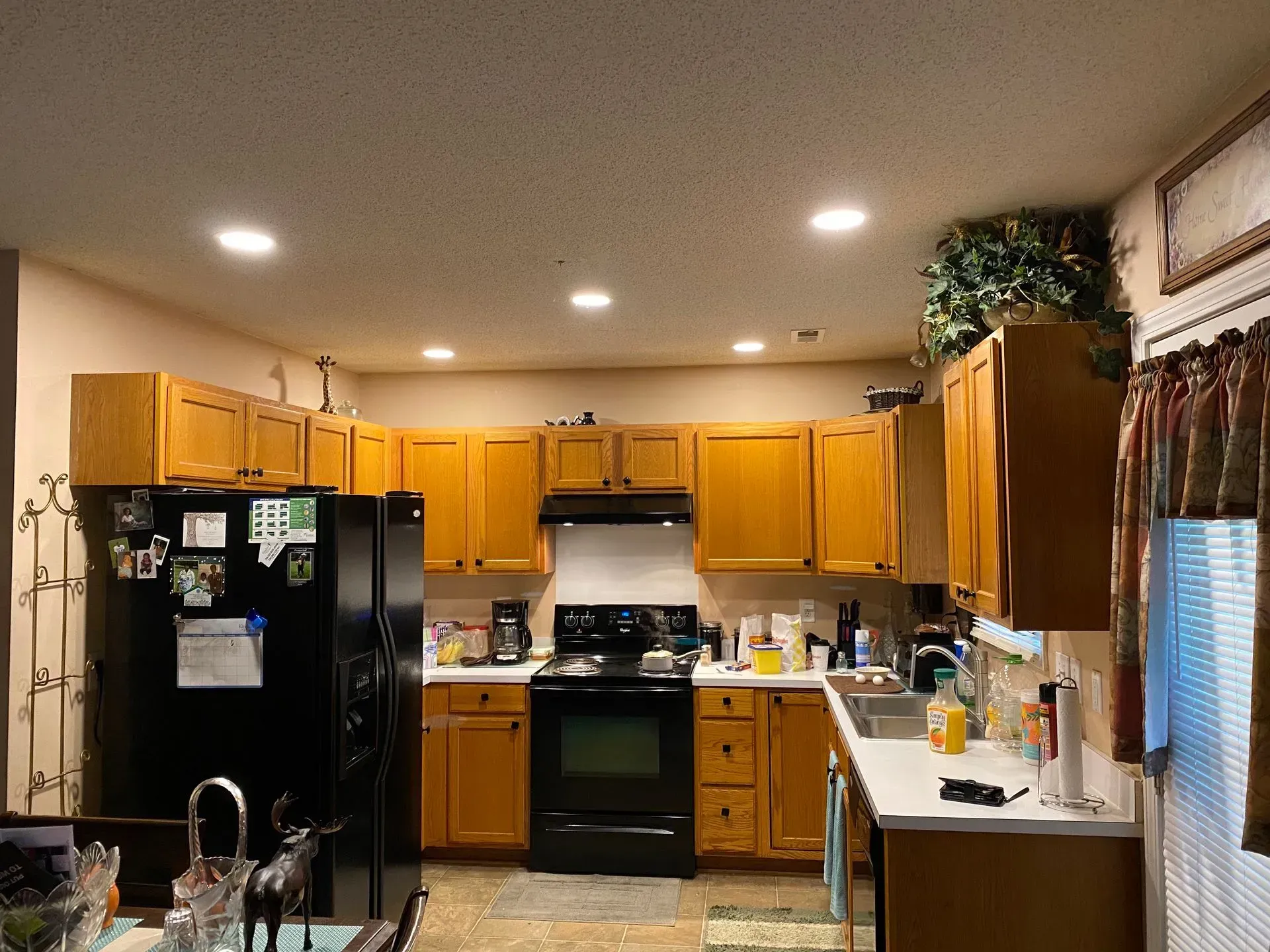 A kitchen with wooden cabinets, black appliances, and white countertops.