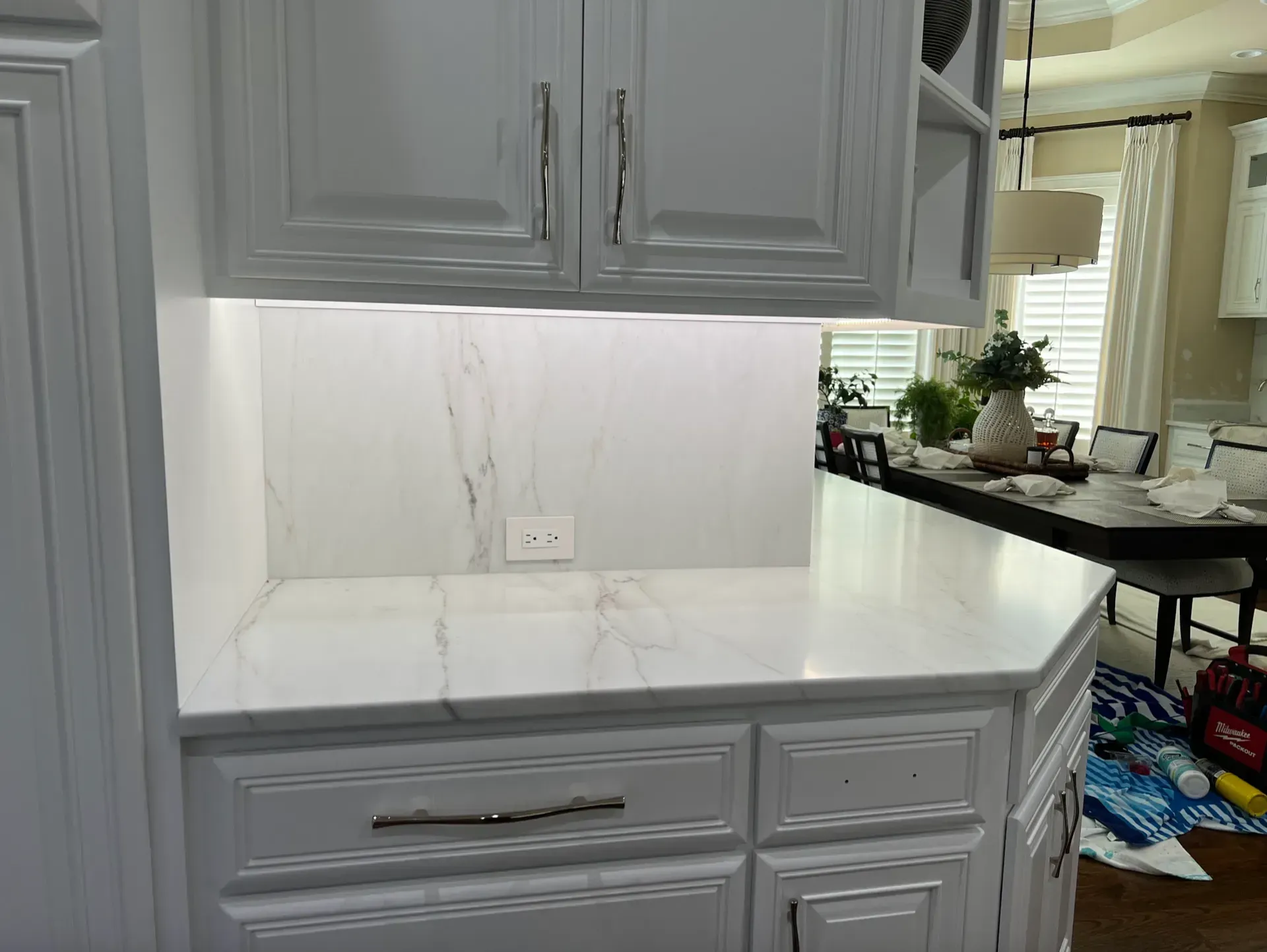 White kitchen island with marble countertop, cabinets, and under-cabinet lighting.