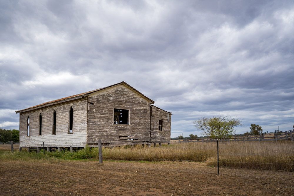 An Old Wooden Building With A Fence In Front Of It — Professional Security Guards in Chinchilla, QLD