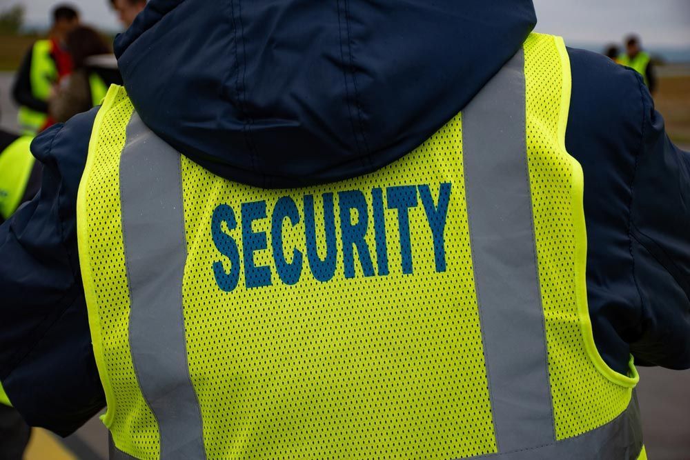 A Person Wearing A Yellow Vest That Says Security — Professional Security Guards in Blackwater, QLD